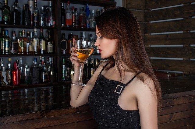 A woman drinking a glass of wine in a bar.
