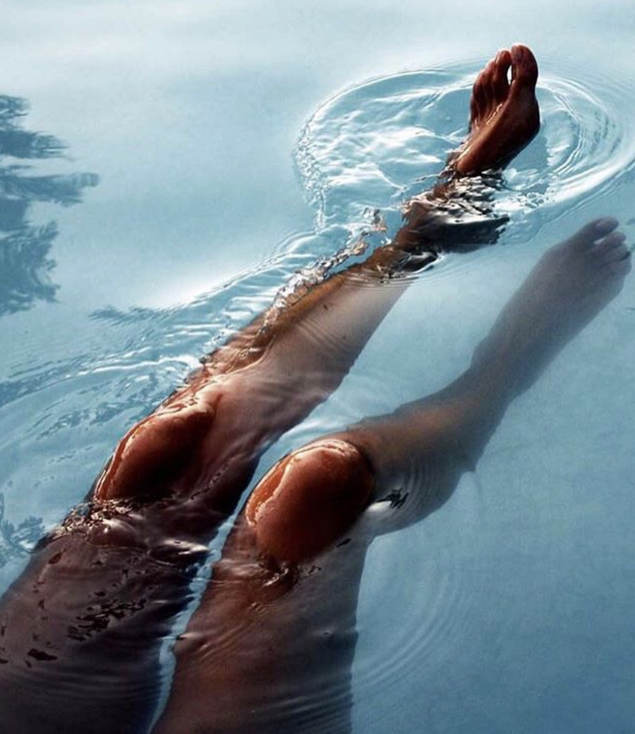 A person's legs floating in water.