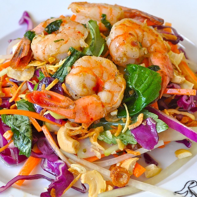 A plate of shrimp salad with red cabbage and carrots.
